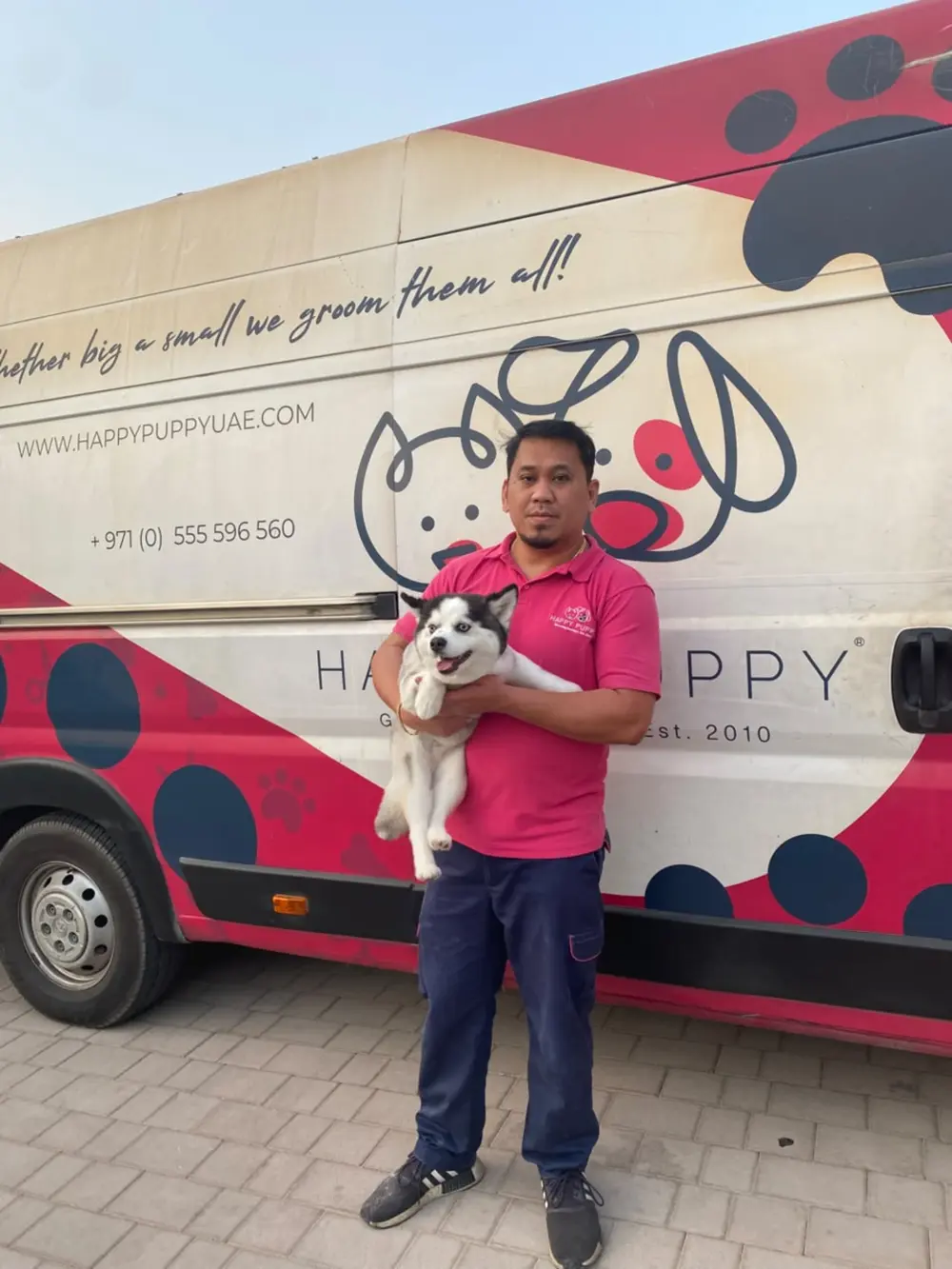Happy Puppy groomer with a husky outside the grooming van